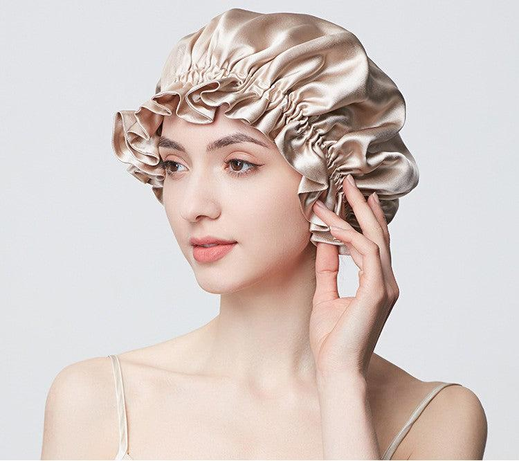 Lifestyle photograph of a model wearing a champagne ruffled-edge mulberry silk bonnet; illustrative styling image.